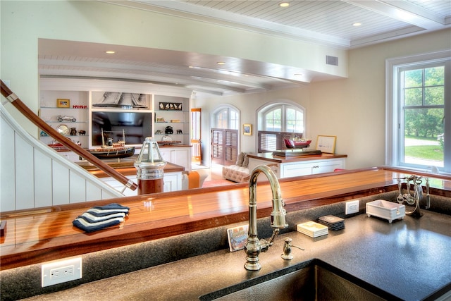 interior space featuring beam ceiling, crown molding, and plenty of natural light