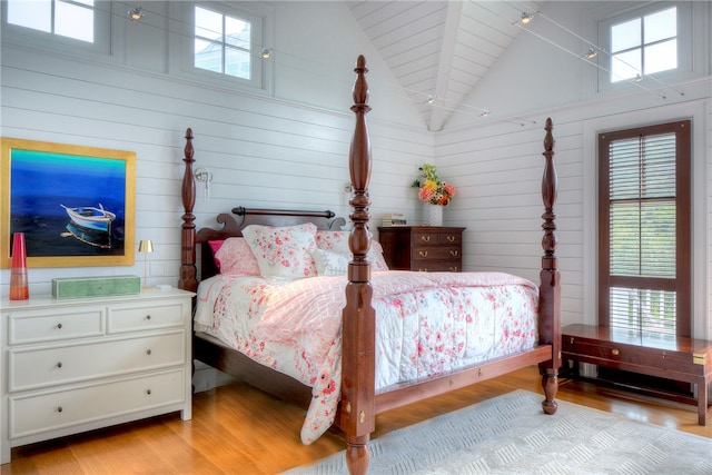 bedroom featuring high vaulted ceiling, beam ceiling, and light hardwood / wood-style floors