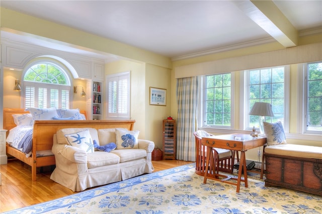 bedroom featuring beamed ceiling, multiple windows, and light hardwood / wood-style flooring