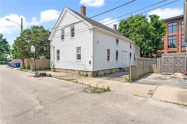 view of property exterior with a chimney and fence