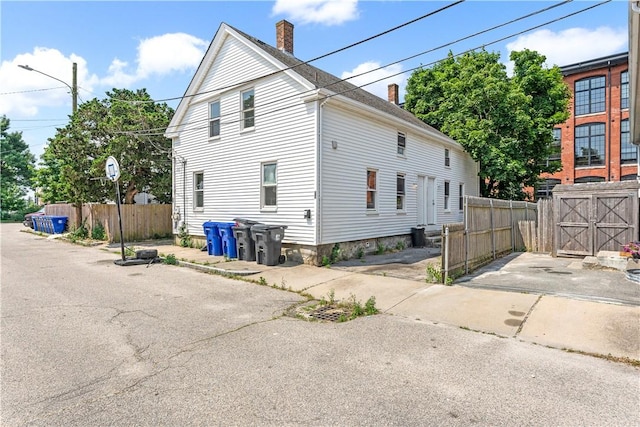 view of property exterior featuring fence and a chimney