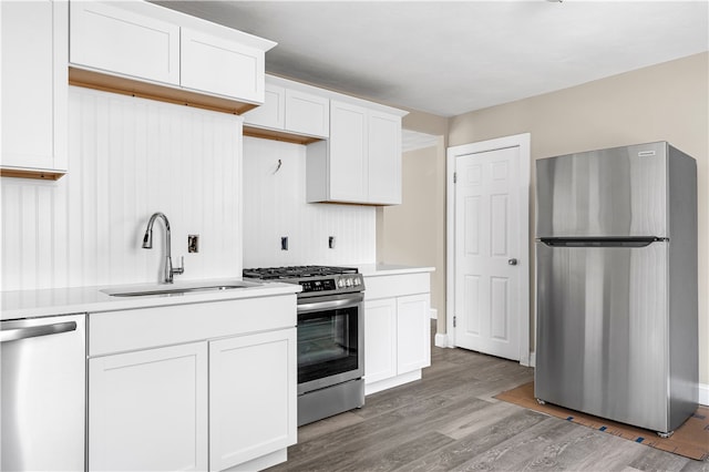 kitchen featuring sink, wood-type flooring, white cabinets, and stainless steel appliances