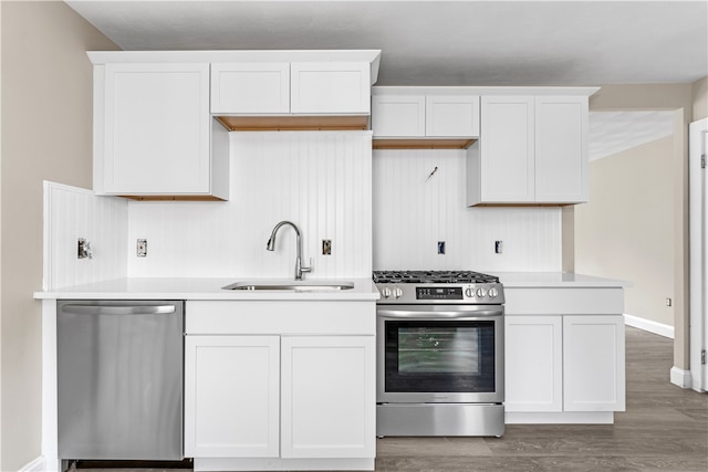 kitchen with sink, wood-type flooring, stainless steel appliances, and white cabinets