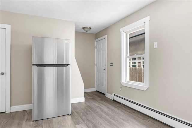 kitchen with stainless steel fridge, a baseboard radiator, and light hardwood / wood-style floors