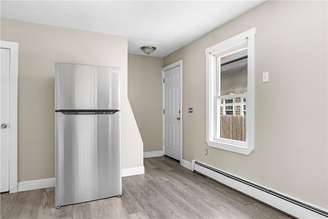 interior space featuring light wood-type flooring, freestanding refrigerator, baseboards, and baseboard heating