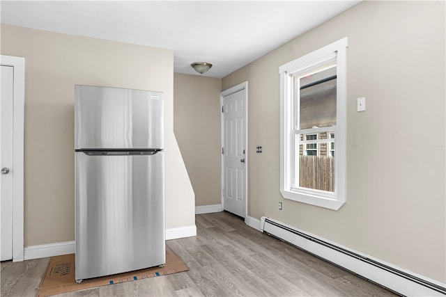 kitchen featuring stainless steel fridge, baseboard heating, and light hardwood / wood-style floors