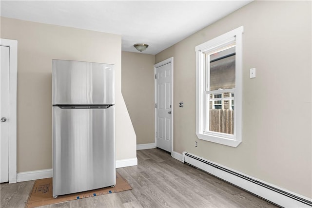 kitchen featuring a baseboard heating unit, freestanding refrigerator, baseboards, and wood finished floors