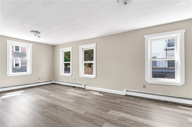 unfurnished room with a baseboard heating unit and wood-type flooring