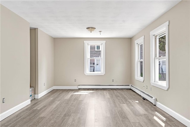 unfurnished room with baseboard heating, baseboards, and wood finished floors