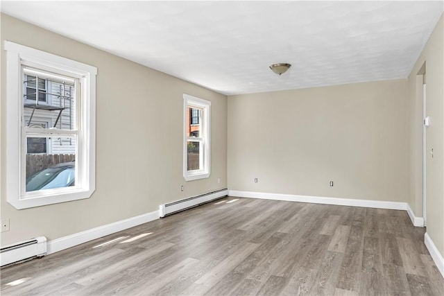 empty room featuring a baseboard radiator, baseboards, and wood finished floors