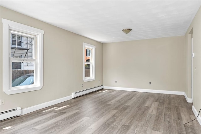 unfurnished room featuring a baseboard heating unit, wood finished floors, and baseboards