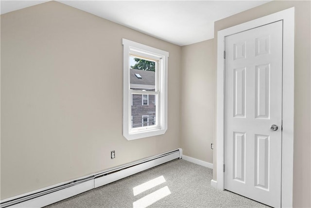 empty room featuring a baseboard heating unit, carpet, and baseboards