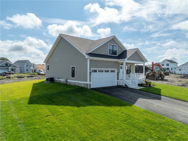 view of front of home featuring a front yard, a garage, covered porch, and central AC