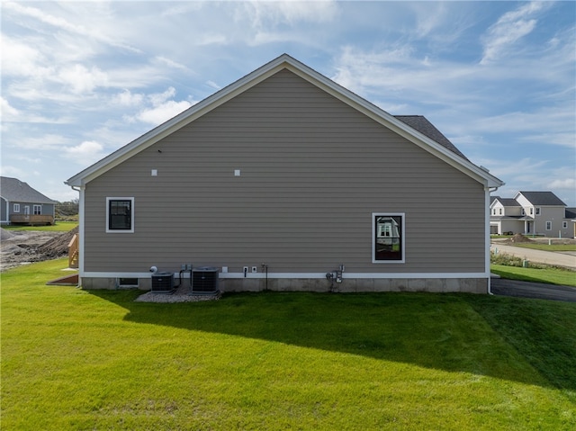 view of home's exterior with central air condition unit and a lawn