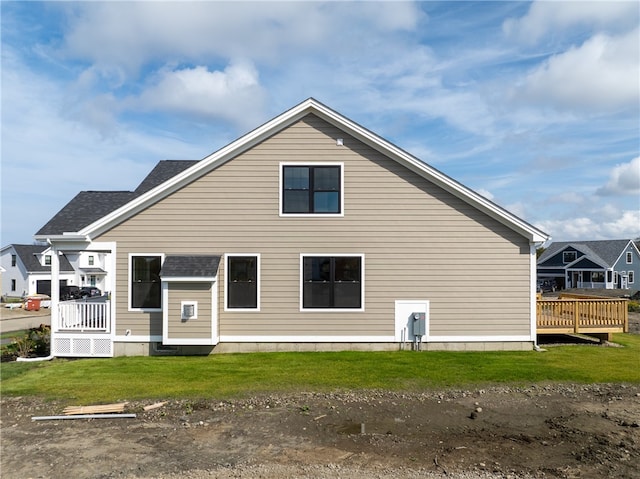 rear view of house with a wooden deck and a yard