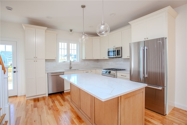 kitchen featuring plenty of natural light, a center island, stainless steel appliances, and white cabinets