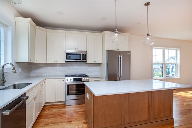 kitchen featuring appliances with stainless steel finishes, a center island, white cabinetry, and sink