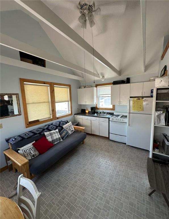 kitchen featuring ceiling fan, beamed ceiling, high vaulted ceiling, white appliances, and white cabinets