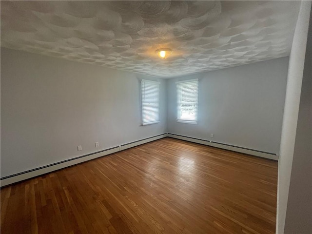 spare room with wood-type flooring, a textured ceiling, and a baseboard radiator