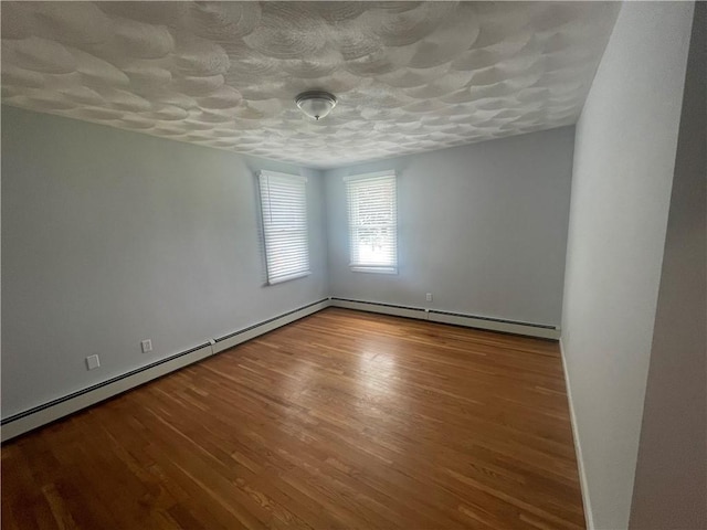 spare room with wood-type flooring and baseboard heating