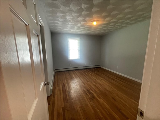 empty room with hardwood / wood-style floors and a baseboard radiator