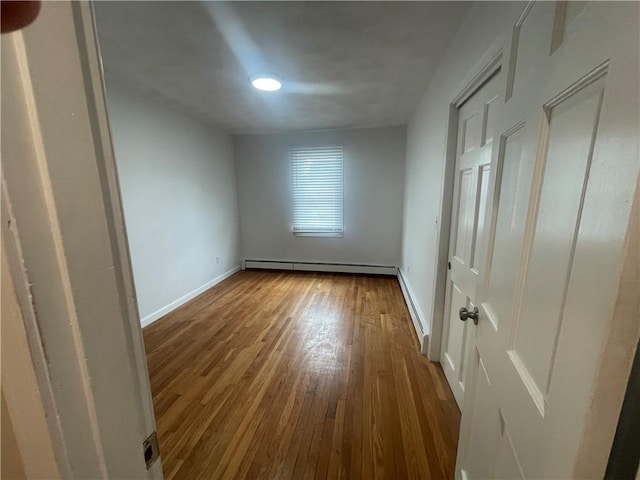 empty room with a baseboard heating unit and hardwood / wood-style floors