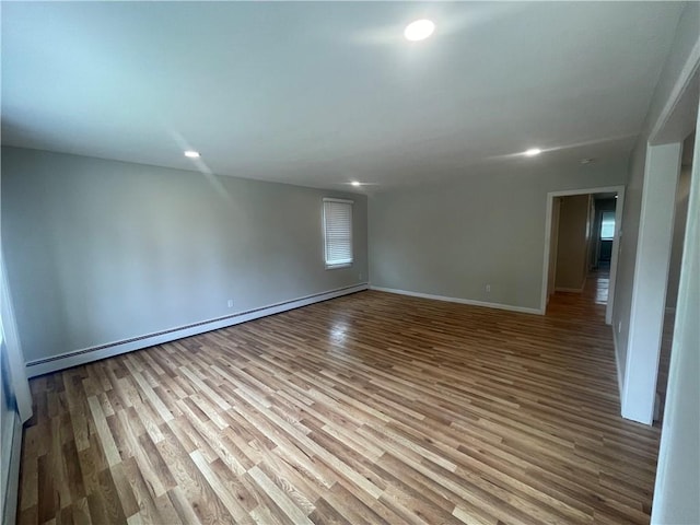 unfurnished room with baseboard heating and light hardwood / wood-style flooring