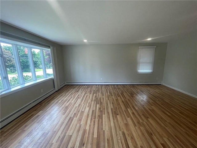 empty room featuring a baseboard radiator and light hardwood / wood-style flooring