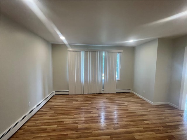 empty room with wood-type flooring and a baseboard heating unit