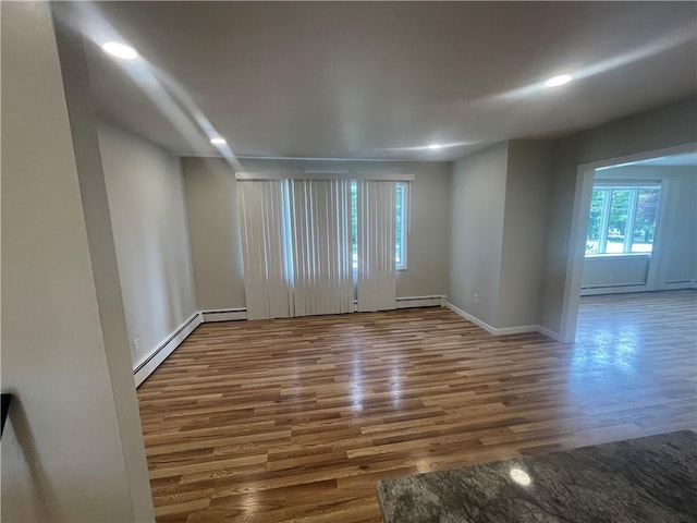 empty room featuring dark wood-type flooring and a baseboard heating unit