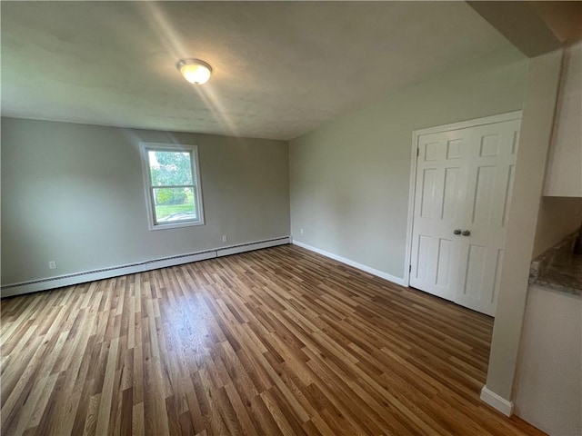 unfurnished room featuring hardwood / wood-style flooring and baseboard heating