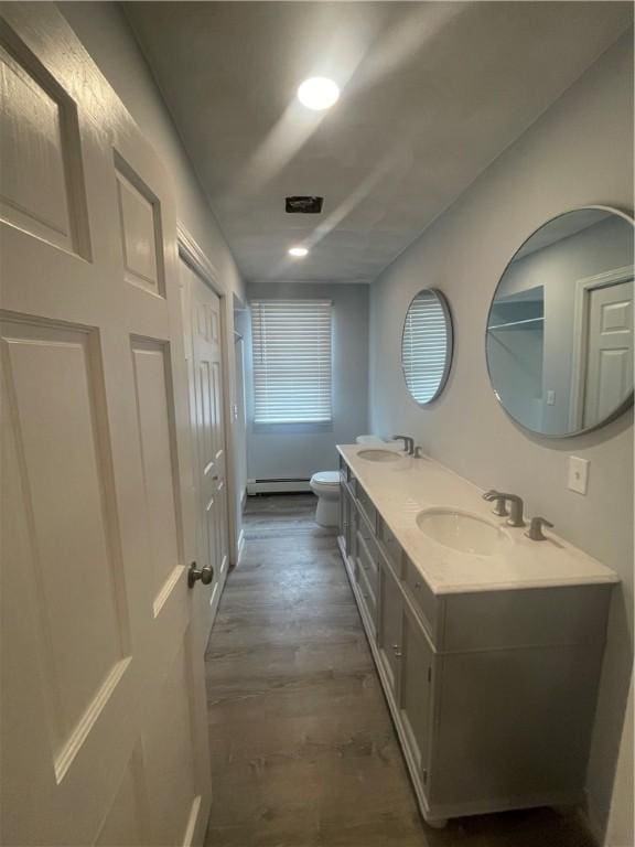 bathroom featuring hardwood / wood-style flooring, vanity, toilet, and a baseboard heating unit