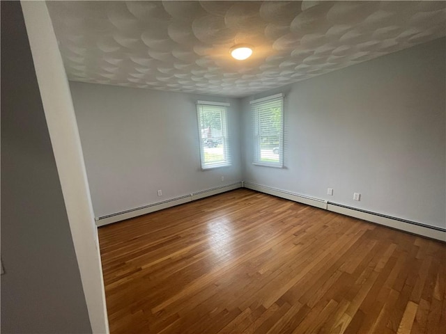 unfurnished room with hardwood / wood-style floors and baseboard heating