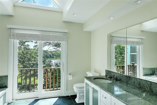 bathroom with vanity, toilet, a healthy amount of sunlight, and tile patterned flooring