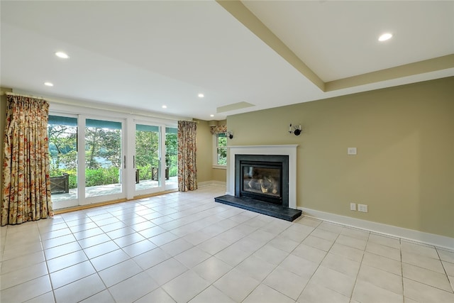 unfurnished living room with a wealth of natural light, light tile patterned floors, and a tray ceiling