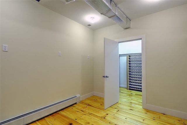 unfurnished room with a baseboard radiator and light hardwood / wood-style flooring