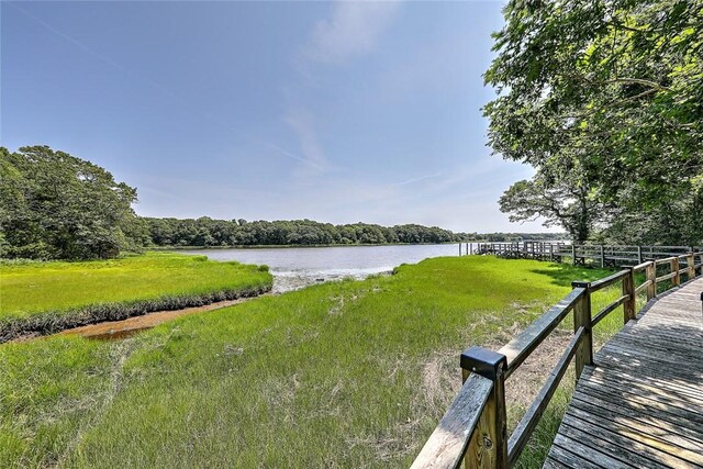 view of dock with a yard and a water view