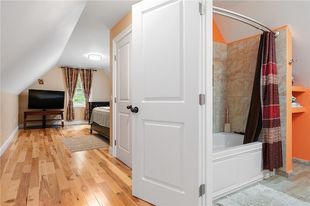 bathroom featuring shower / bath combo, wood-type flooring, and vaulted ceiling