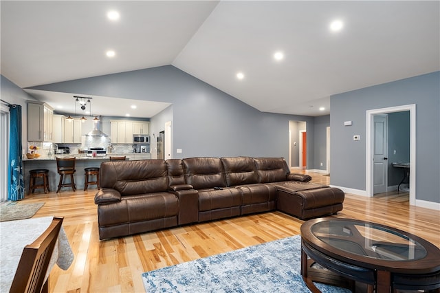 living room featuring sink, vaulted ceiling, and light hardwood / wood-style floors