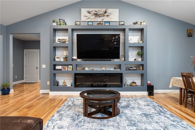 living room featuring built in features, vaulted ceiling, and hardwood / wood-style floors