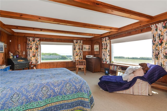 carpeted bedroom with multiple windows, beam ceiling, and wood walls