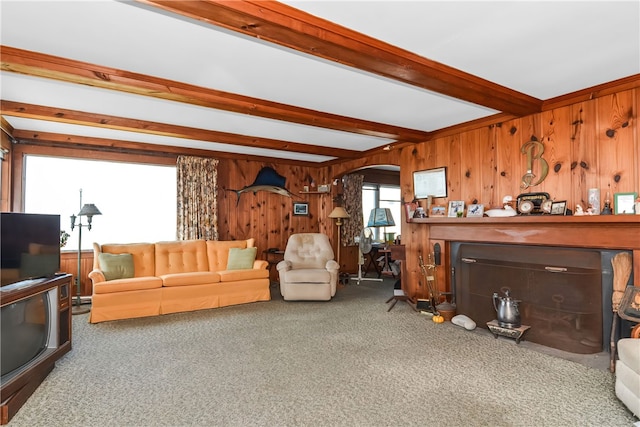 living room with carpet flooring, wood walls, and beamed ceiling