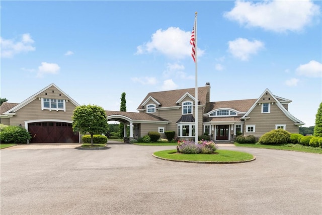 view of front of home with curved driveway, a garage, and a chimney