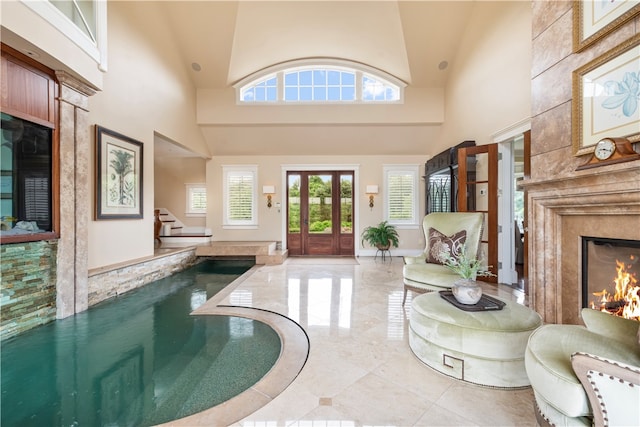 tiled foyer with a premium fireplace, french doors, and a towering ceiling