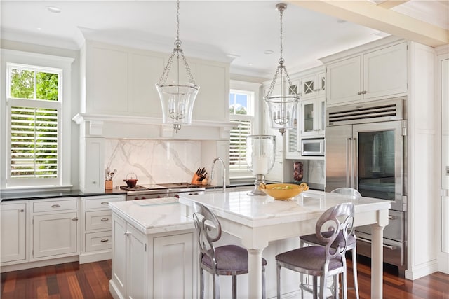 kitchen with built in appliances, tasteful backsplash, dark hardwood / wood-style floors, and a kitchen island