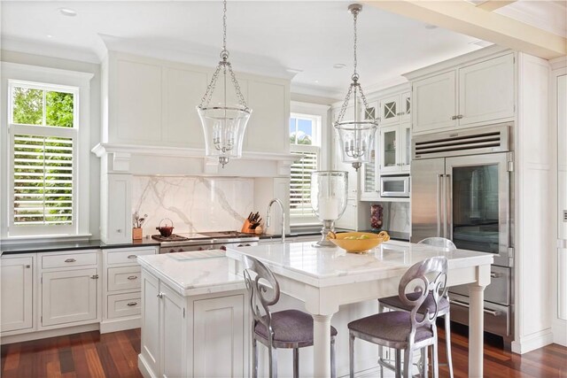 kitchen featuring a kitchen island with sink, dark wood-style floors, a breakfast bar area, and stainless steel appliances