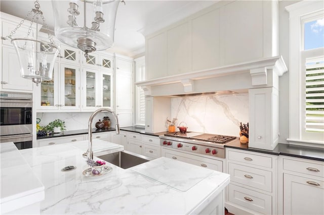 kitchen featuring a sink, white cabinetry, tasteful backsplash, glass insert cabinets, and stainless steel appliances