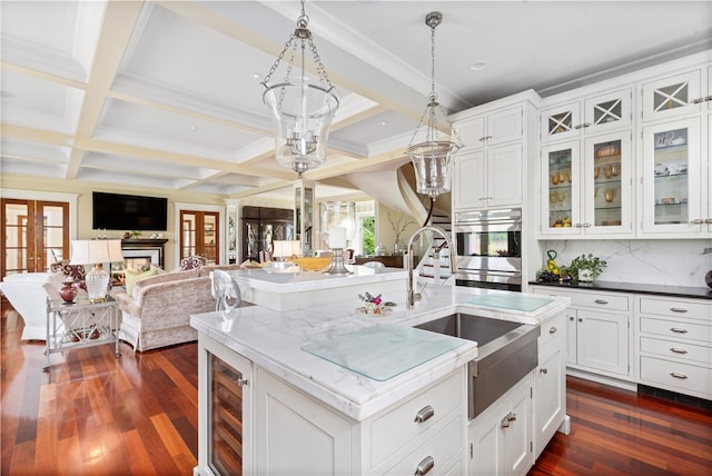 kitchen featuring decorative light fixtures, a kitchen island with sink, beam ceiling, dark wood-type flooring, and coffered ceiling