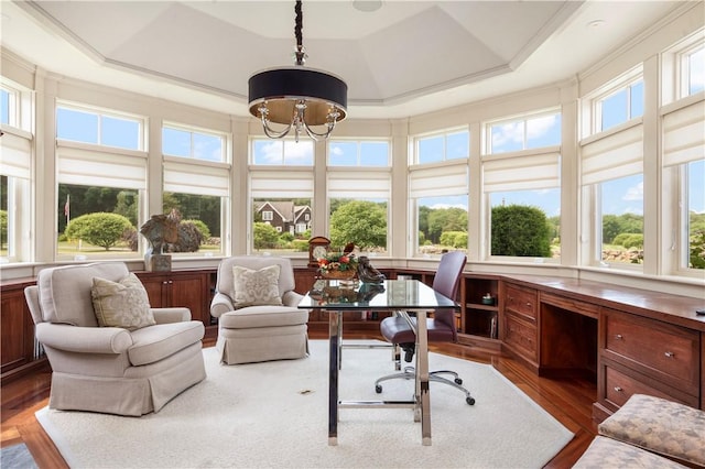 sunroom / solarium featuring a raised ceiling, crown molding, a chandelier, and wood finished floors