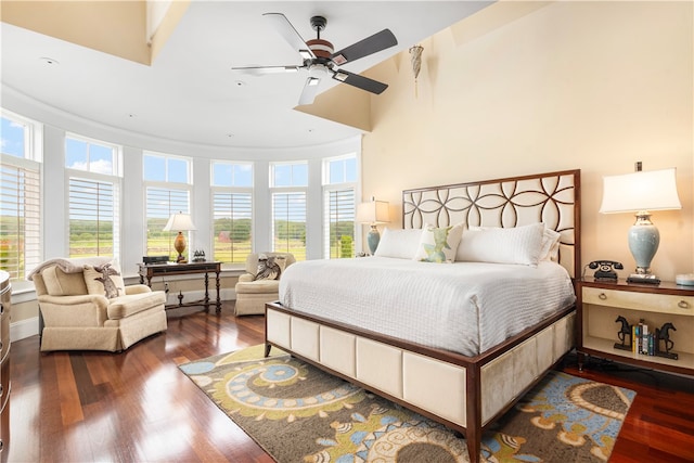 bedroom with dark wood-type flooring, ceiling fan, and a towering ceiling